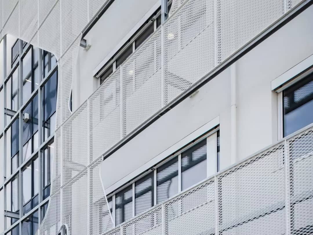 A high-quality ansusmetal expanded metal building facade showcasing a modern diamond pattern and industrial aesthetic