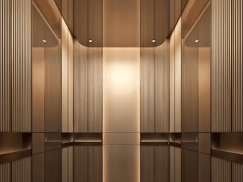 A luxurious, symmetrical interior space, likely an elevator, featuring warm bronze-toned vertical fluting and highly reflective surfaces with soft, recessed lighting